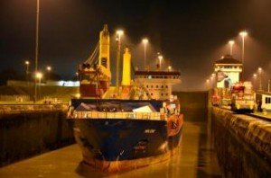 Conatainer ship is illuminated as it passes through the Panama Canal at night.