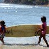 Two young children carry a surfboard to the water in Santa Catalina, Panama