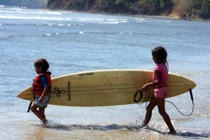 Two young children carry a surfboard to the water in Santa Catalina, Panama